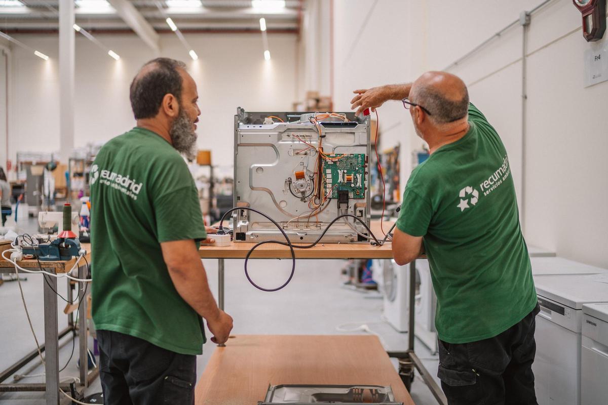 Latif y Julián reparan un horno en la nave de Recumadrid de Villaverde.