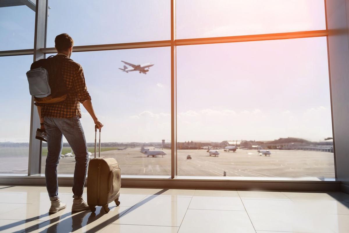 Un hombre y su maleta en un aeropuerto.