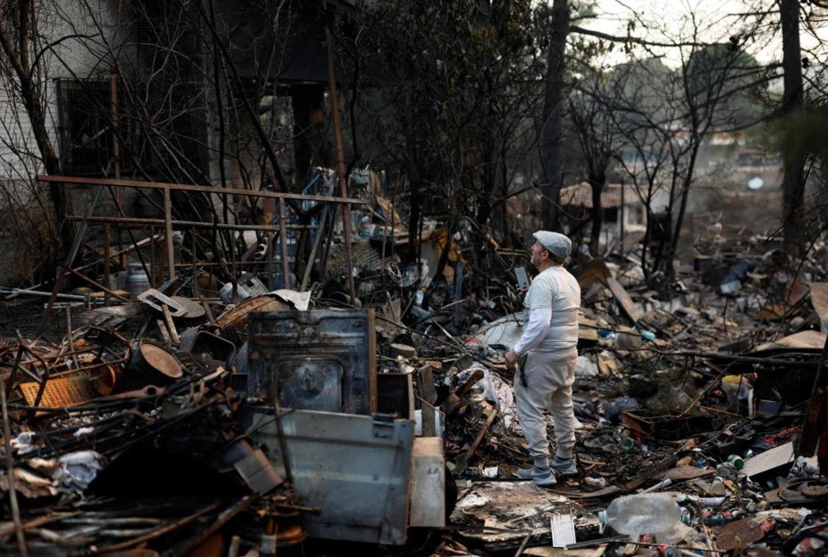 Un veí de Pelayos de la Presa, Madrid, davant casa seva, cremada. | ÓSCAR DEL POZO / AFP