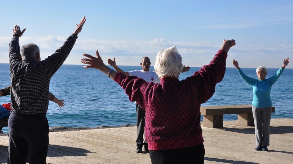 Personas mayores haciendo ejercicio en Barcelona, frente a la playa.