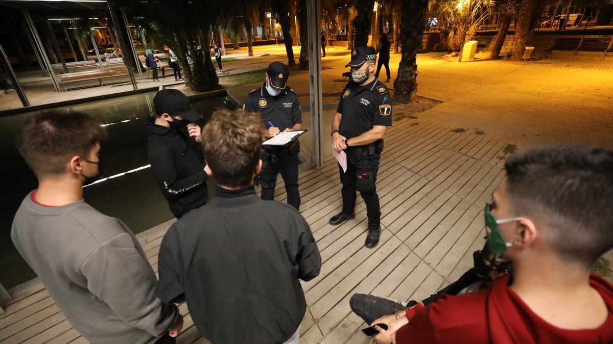 Agentes de la Policía Local de Elche, ayer, identificando e informando a jóvenes de las medidas. 