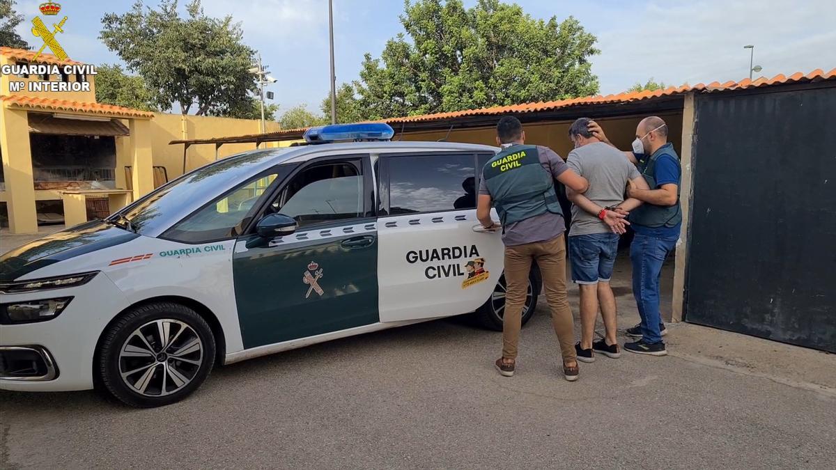 La Guardia Civil introduce en el vehículo a uno de los detenidos por la estafa.