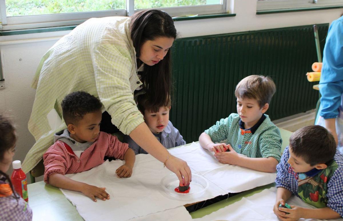 Marina Rosón ayuda a los sos escolinos d’Infantil a estampar sellos en teles.  |  A. VELASCO