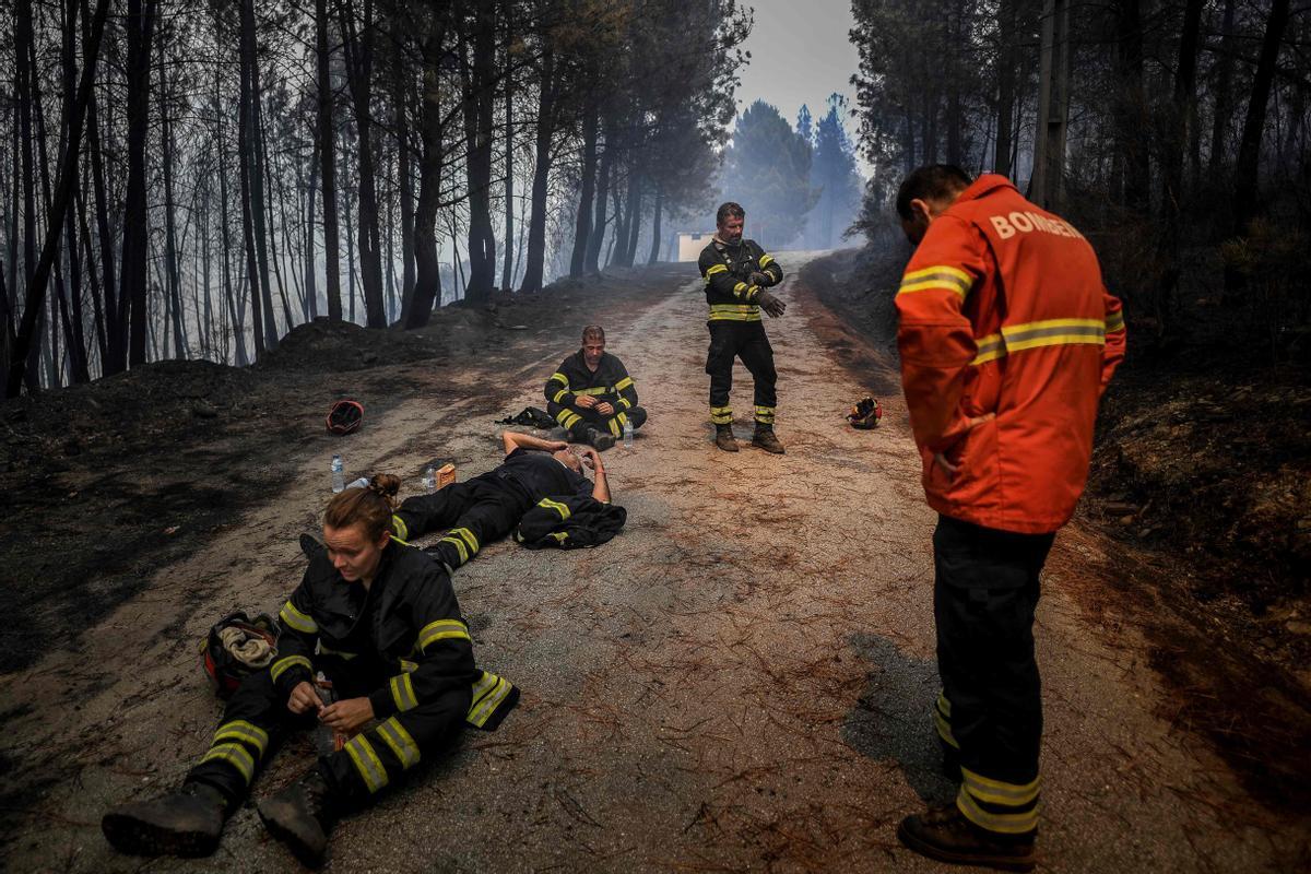 Bomberos beben agua y descansan para recuperarse durante una operación para extinguir un fuego en Sameiro, cerca de Manteigas (Portugal), el 10 de agosto del 2022.