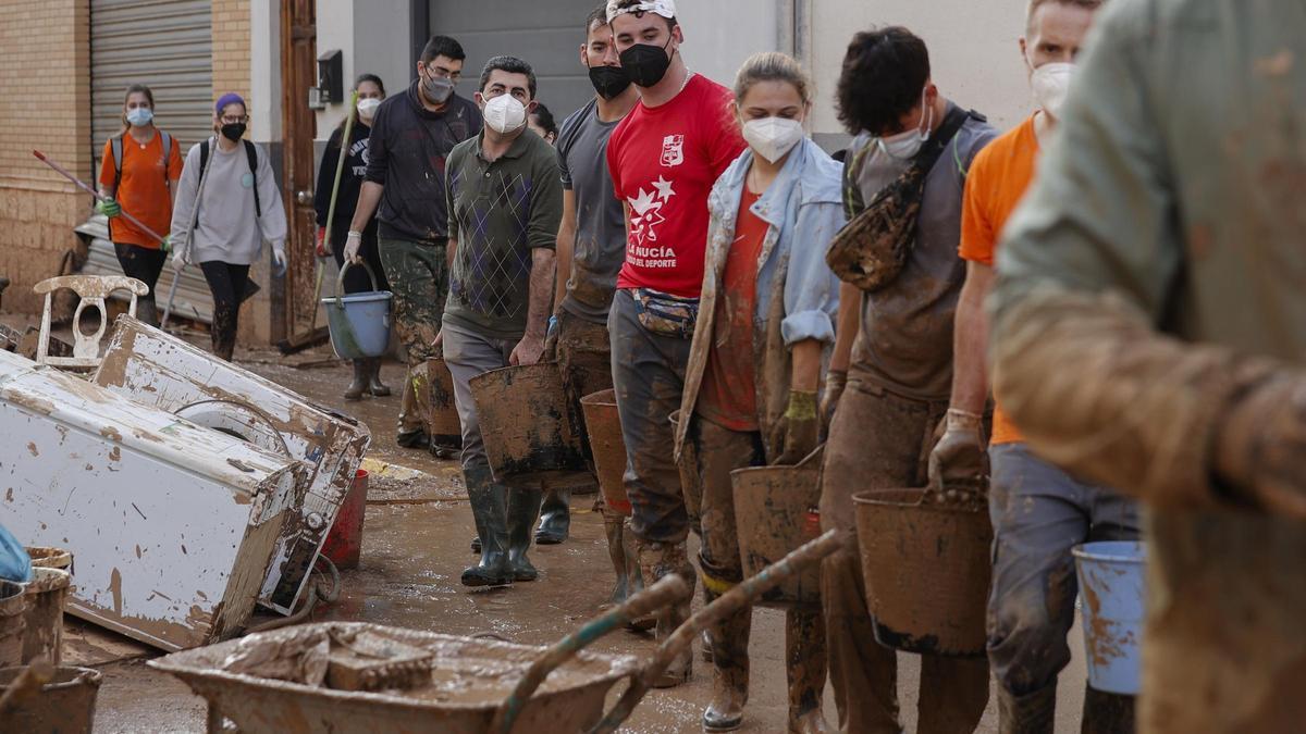 Cadena de jóvenes en labores de limpieza tras la dana.