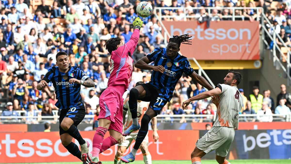 Svilar, el meta del Roma, despeja el balón ante Bisseck, el jugador del Inter, en San Siro.