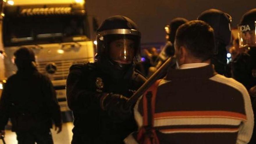 Un Policía amenaza a un miembro de un piquete informativo, esta madrugada en Mercamálaga.