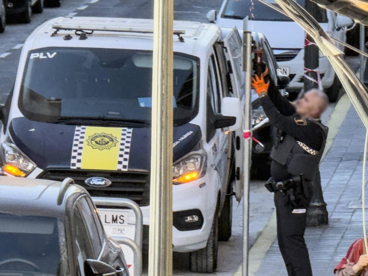 Un agente de Policía Local de València cortando parte de la señal de prohibido aparcar