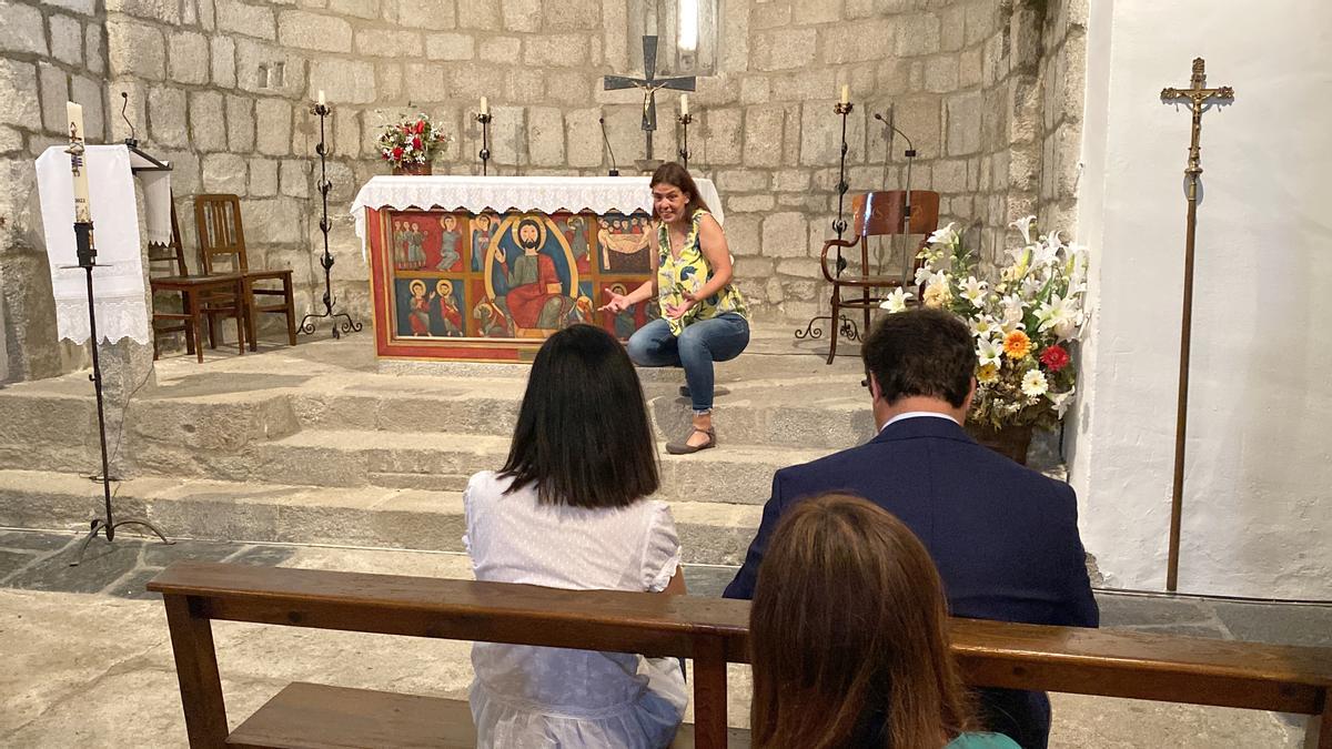 La guia de patrimoni Pilar Aláez explicant què hi ha a l'interior de l'església de Sant Esteve de Guils de Cerdanya i on es veu al president del Consell Comarcal, Isidre Chia, seguint la visita des d'un banc