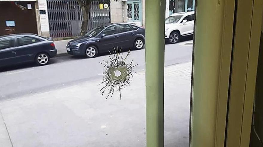 Impacto de la bala que atravesó la puerta de la cafetería y las esquirlas de cristal.