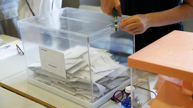 Un miembro de una mesa electoral desprecinta una urna para proceder al recuento en un colegio electoral en Madrid.
