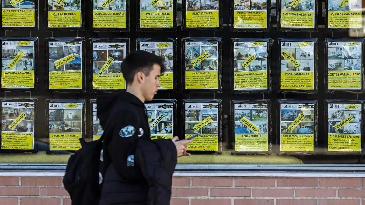 Un joven pasa ante el escaparate de una inmobiliaria.