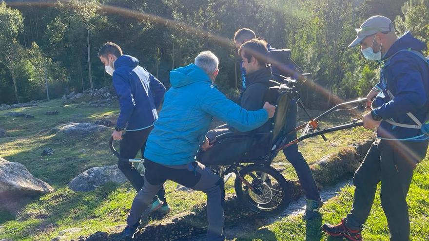 Los voluntarios ayudan a Manuel Sobrino a cruzar un tramo empedrado del camino