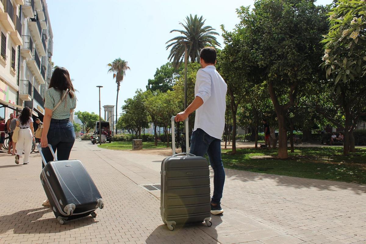 Dos turistas transitan con sus maletas por Málaga.