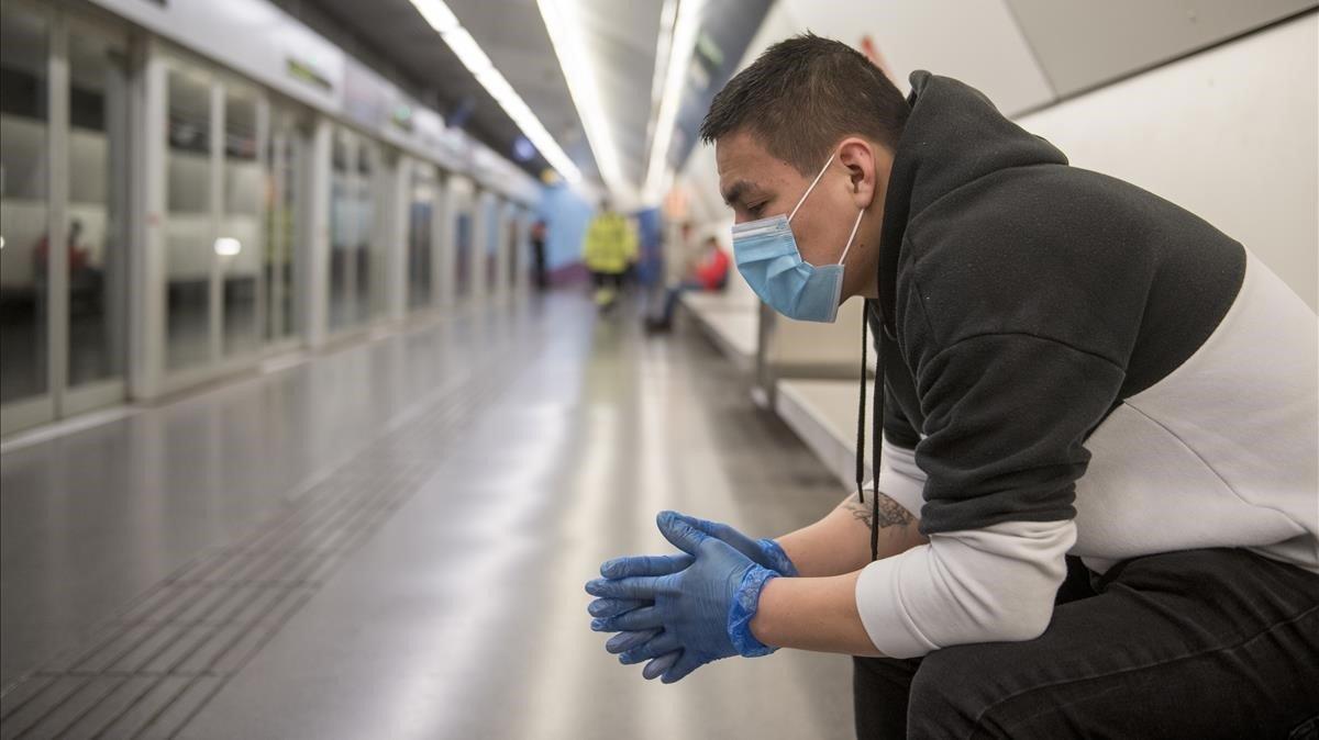 Un joven espera el metro en la estación de Sagrera, en Barcelona, con guantes y mascarilla.