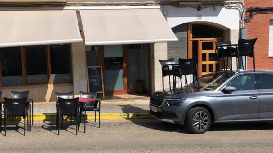 Un bar munta dues taules de la seva terrassa sobre un cotxe aparcat al carrer