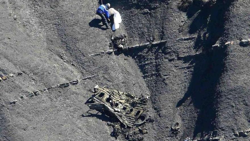 Un rescatador, atado con una cuerda, descuelga un cadáver de una ladera.