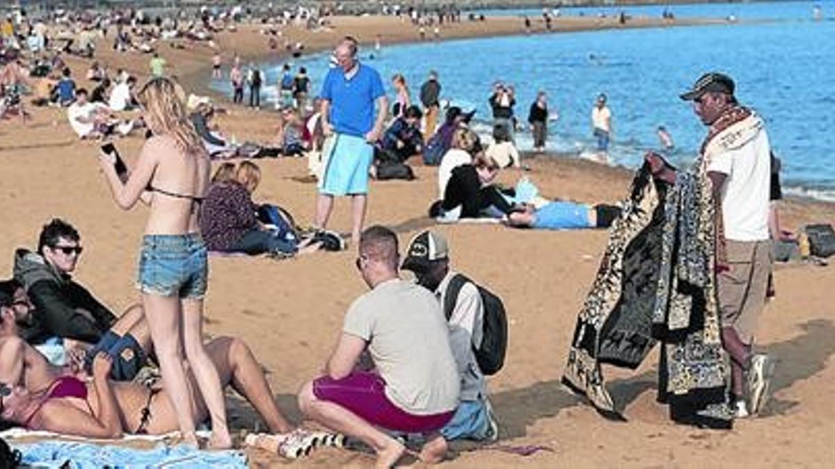 Turistas en la playa de la Barceloneta, ayer, aprovechando el día radiante.