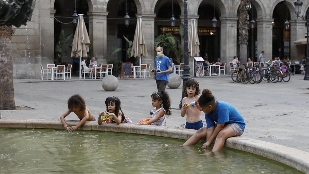 Un grupo de niños juegan en la fuente de la plaza Reial de Barcelona, el 9 de julio