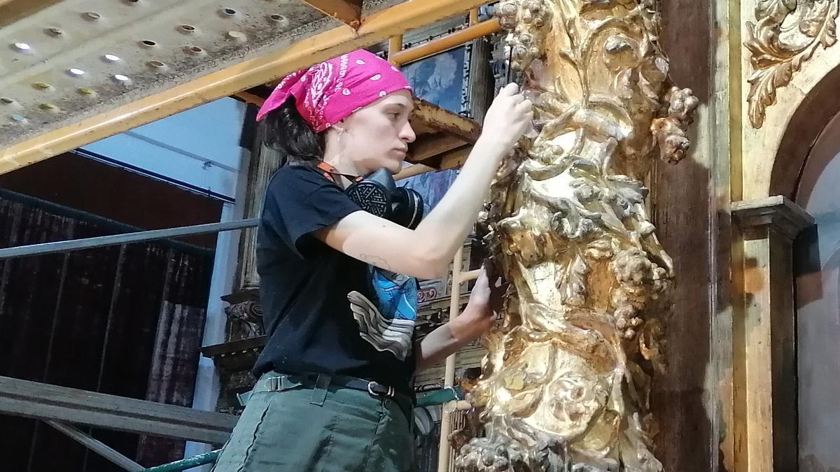 Una estudiante recupera el policromado dorado de uno de los retablos de Tagarabuena