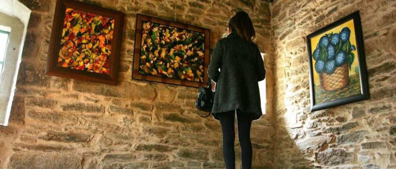 Una joven contempla varios cuadros de Dosinda Alonso en la sala de exposiciones. // Bernabé/Luismy