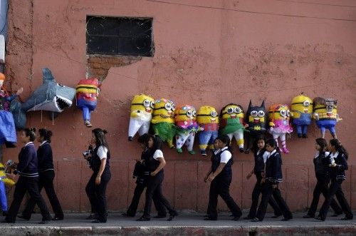 College students walk past below pinatas, including those in shape of Minions from movie "Despicable Me", in downtown Guatemala City