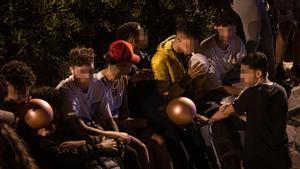 Varios jóvenes inhalan óxido nitroso con globos en el macrobotellón de la playa de Bogatell.