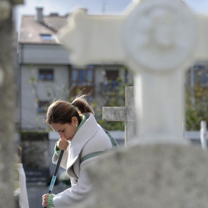 Una mujer limpia una tumba en el antiguo cementerio de Lalín.