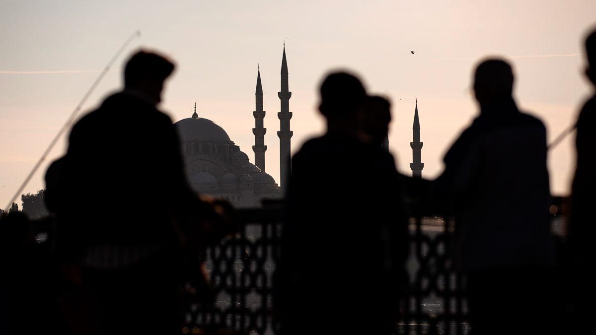 Varias personas caminan junto al puente de Galata, frente a la mezquita de Suleimán, en Estambul