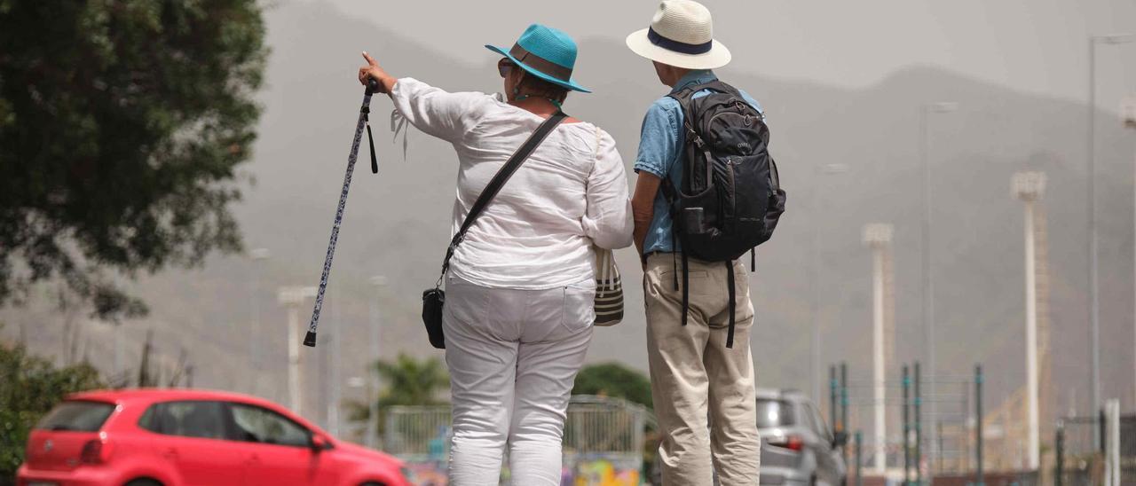 Dos turistas bajo el espeso manto de calima y el calor en Santa Cruz.