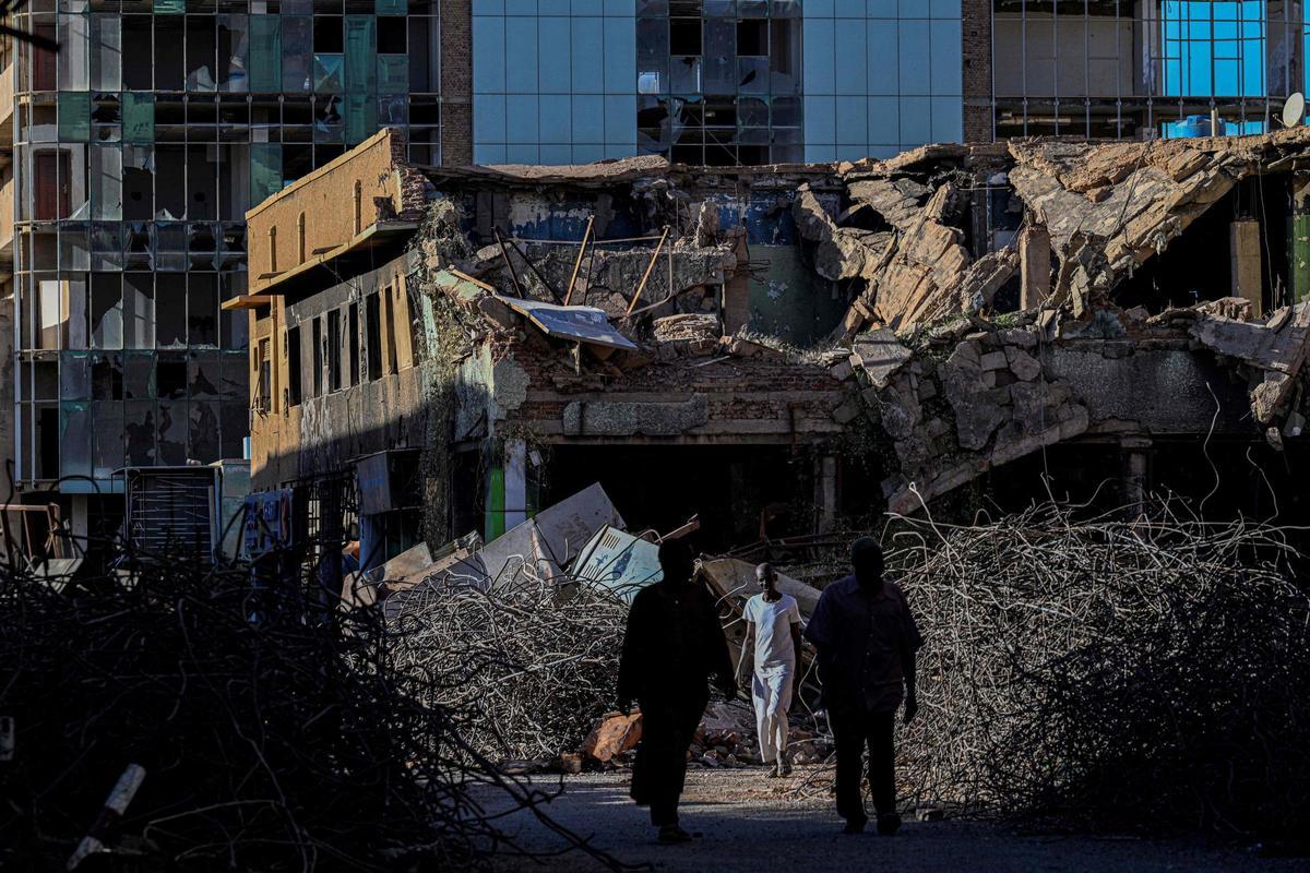 Hombres sudaneses caminan junto a un edificio destruido en la capital, Jartum, el 16 de abril de 2026. De los casi cuatro millones de personas —aproximadamente la mitad de la población de Jartum antes de la guerra— que huyeron durante el conflicto, más de 1,8 millones han regresado en el último año. Sin embargo, según las Naciones Unidas, menos de 80.000 personas han vuelto al centro de Jartum.