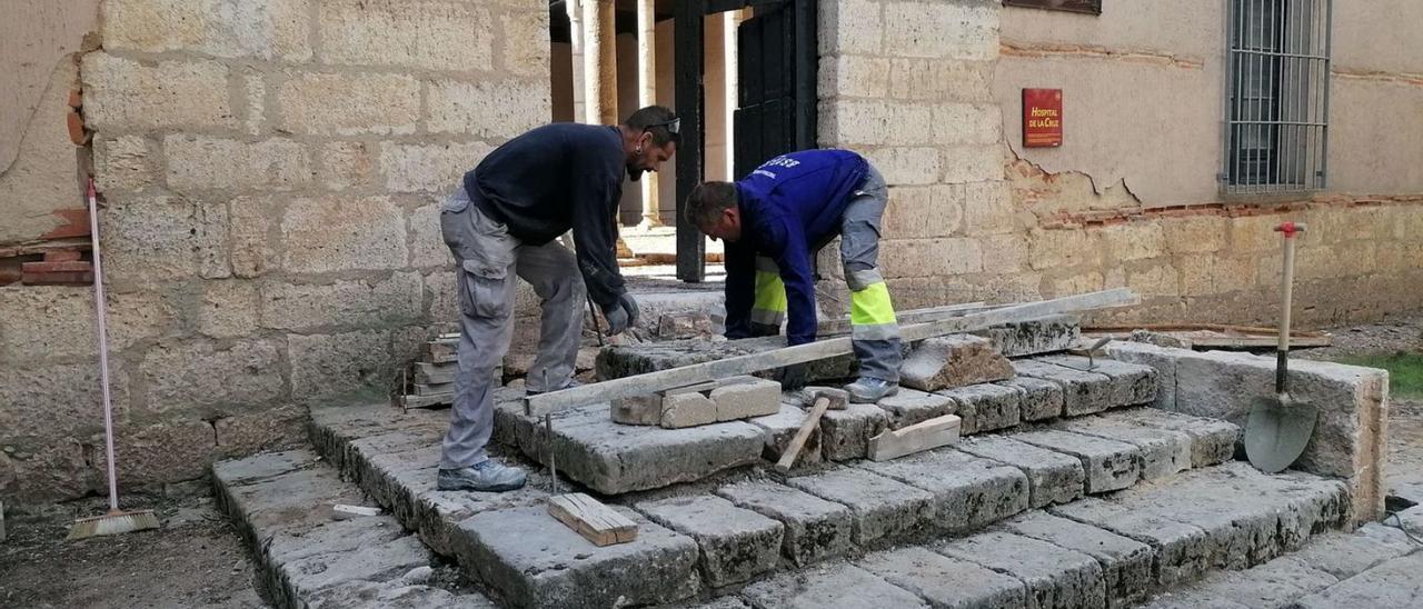 Dos operarios trabajan en la recolocación de las piedras de la escalera de acceso al histórico edificio. | M. J. C.