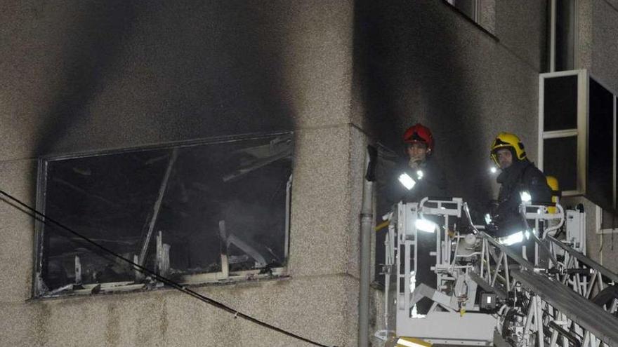 Los bomberos, en una de las ventanas de la vivienda de O Birloque.