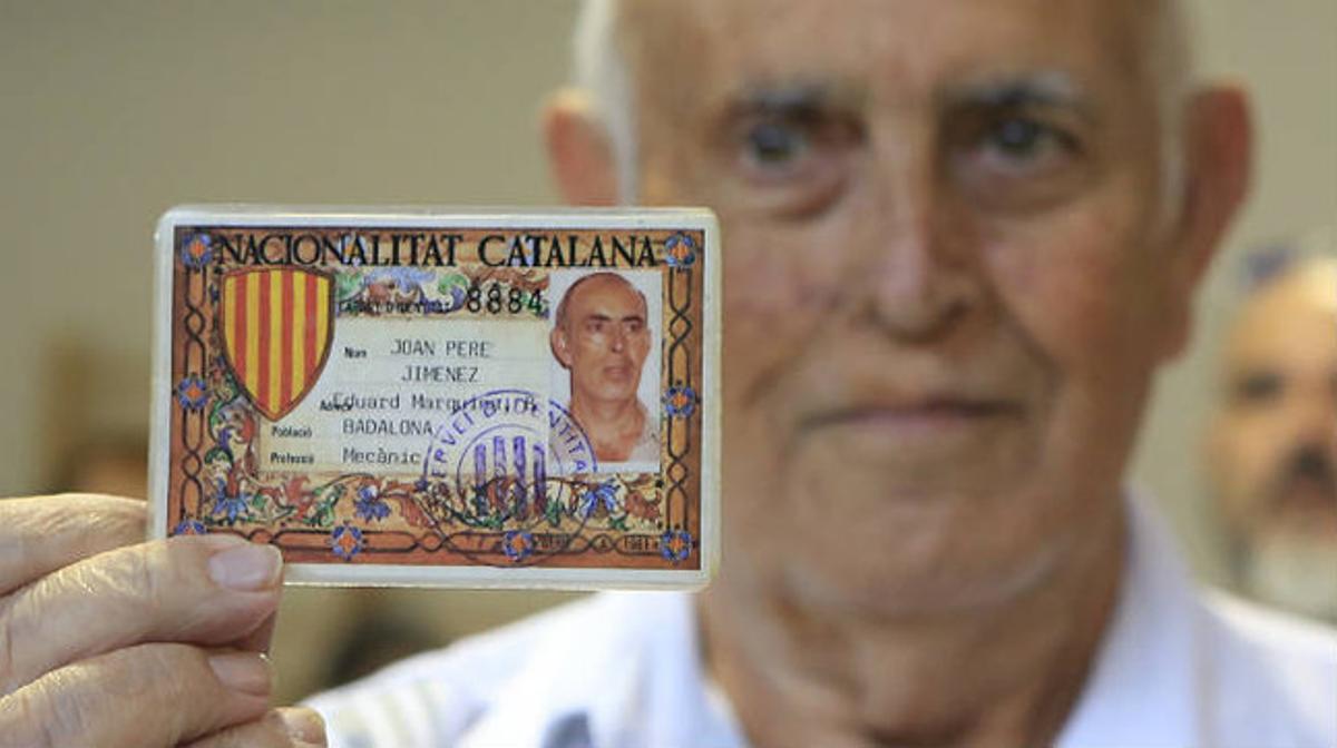 Un hombre muestra un DNI con nacionalidad catalana en el colegio electoral Lola Anglada de Badalona.