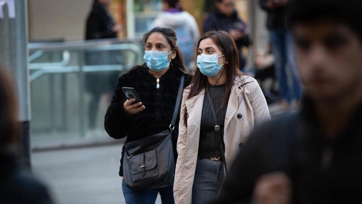 Dos mujeres con mascarilla por el centro de Barcelona