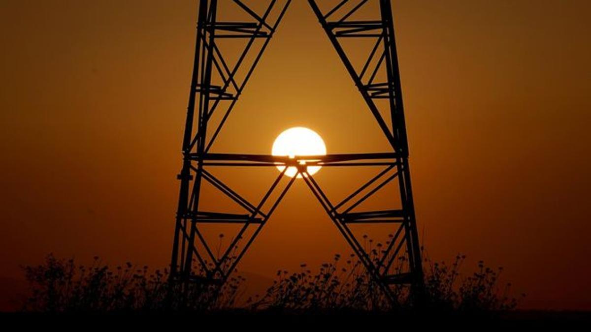 Una torre de electricidad con el sol de fondo.