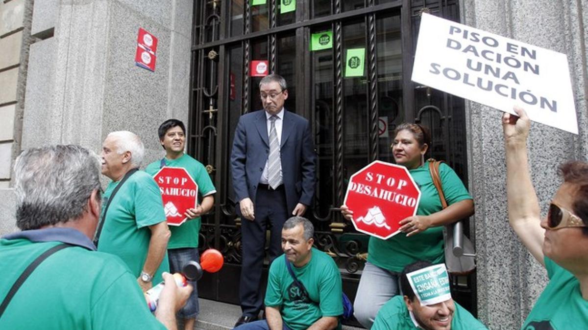 People obstruct a worker's pathway as they block a door during a protest against evictions at the BBVA bank office of Barcelona