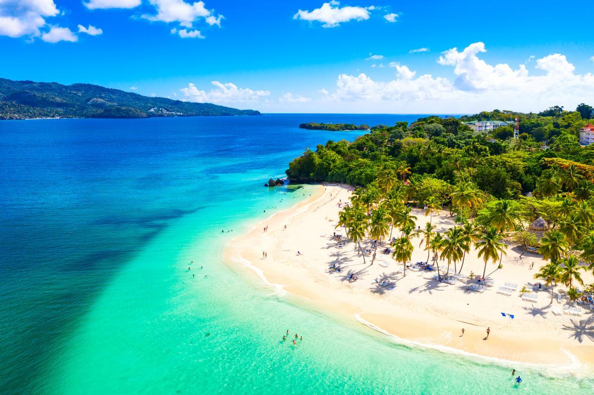 Arena fina, aguas azul turquesa y un paisaje verde de fondo: bienvenidos al Caribe.