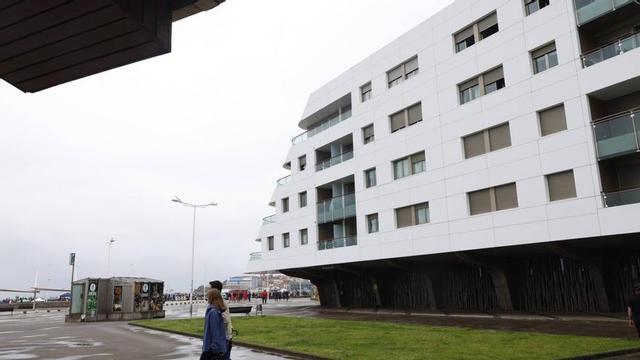 Paseantes ante un bloque de viviendas en el entorno de Poniente, con la playa al fondo y en las proximidades del paseo de Naval Azul. | MIKI LÓPEZ