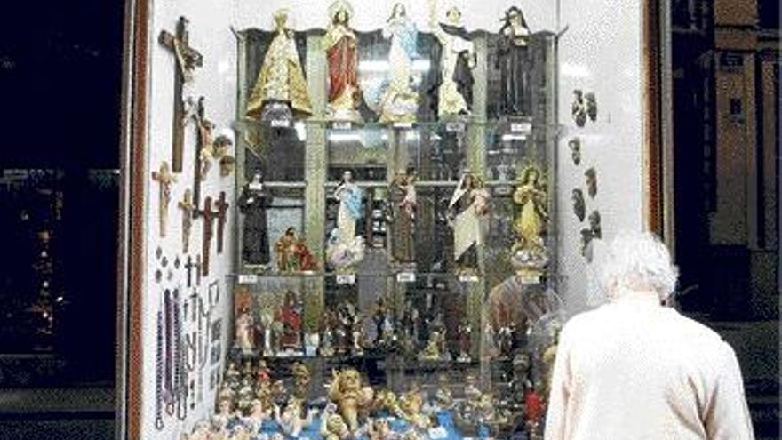Una mujer mira varias figuras del Niño Jesús expuestas junto a otros objetos