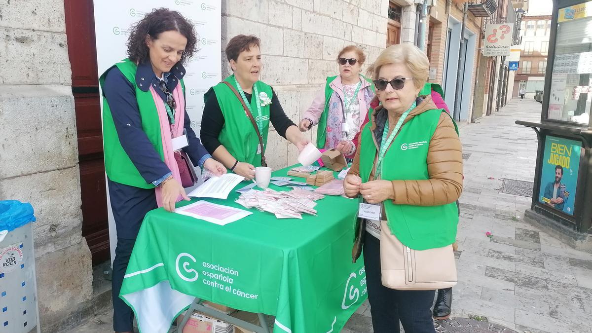 Voluntarias de la AECC se disponen a repartir lazos rosas entre los vecinos