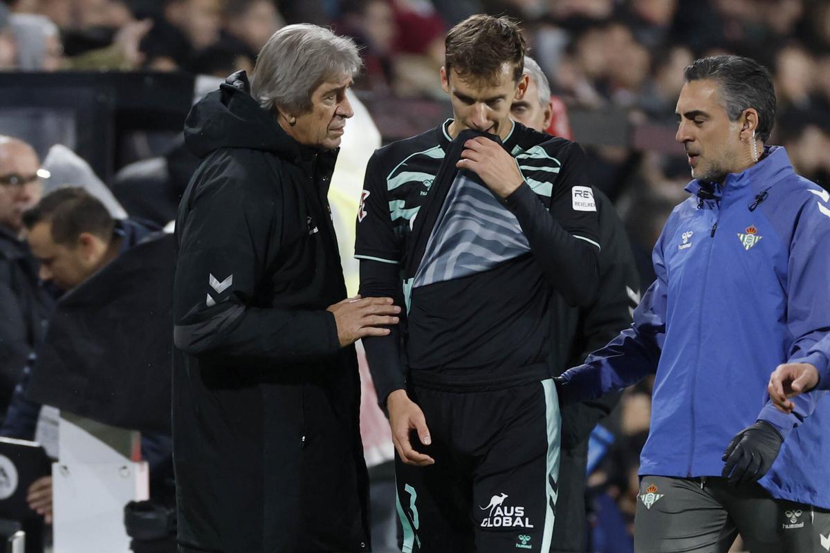 El entrenador del Betis, Manuel Pellegrini (i), anima a Diego Llorente (c) al abandonar el terreno de juega lesionado.