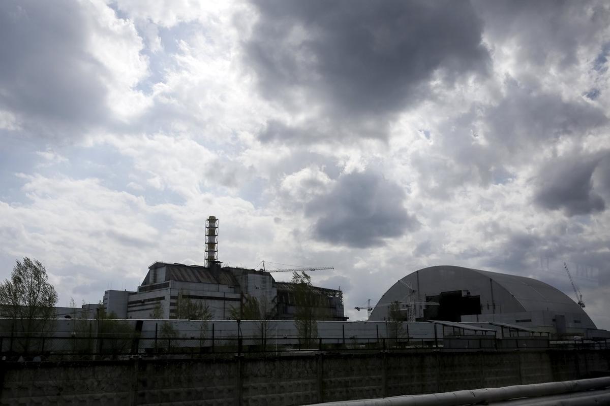 A general view shows a containment shelter for the damaged fourth reactor (L) and the New Safe Confinement (NSC) structure (R) at the Chernobyl Nuclear Power Plant, Ukraine April 22, 2016. Picture taken through a bus window.  REUTERS/Gleb Garanich