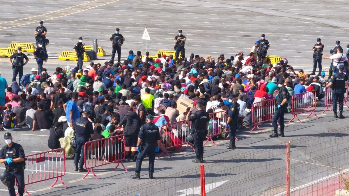Varios migrantes desalojados de la playa del Trampolín esperan a ser reubicados, a 20 de agosto de 2026, en Ceuta (España). La Policía ha comenzado a desalojar el campamento improvisado de migrantes en la playa del Trampolín de Ceuta. La ciudad autónoma sigue afrontando una grave crisis humanitaria después de la histórica entrada masiva de más de 70.000 migrantes a nado por el Tarajal durante los días 30 y 31 del pasado mes de julio. 20 AGOSTO 2026 Marcos Moreno / Europa Press 20/08/2026. Marcos Moreno;
