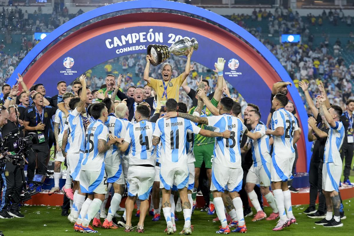 Argentinas kitman Mario De Stefano holds up the trophy as he celebrates with players after defeating Colombia in the Copa America final soccer match in Miami Gardens, Fla., Monday, July 15, 2024. (AP Photo/Rebecca Blackwell) / EDITORIAL USE ONLY/ONLY ITALY AND SPAIN