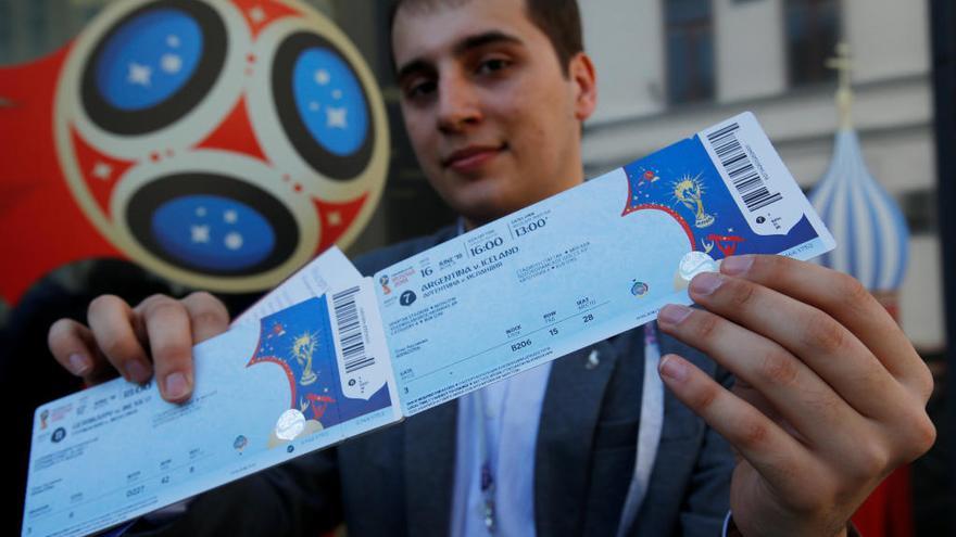 Un aficionado muestra las entradas que acaba de comprar