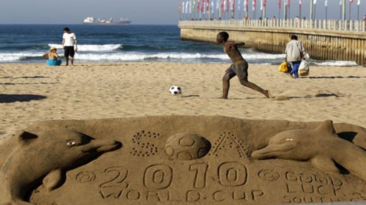 Un nen juga a futbol a la platja de Durban.