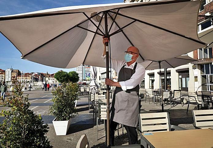 El hostelero Ignacio Robles colocando una sombrilla.