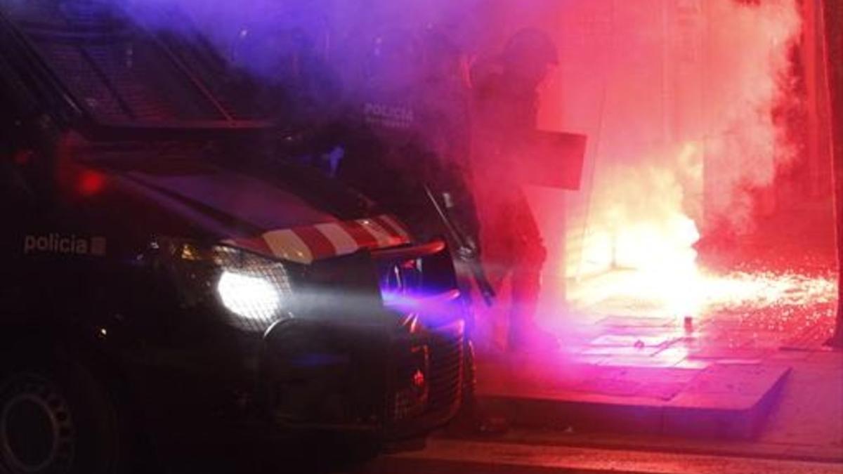 Varios mossos intentan sofocar uno de los incendios provocados por los radicales, anoche en Gràcia.