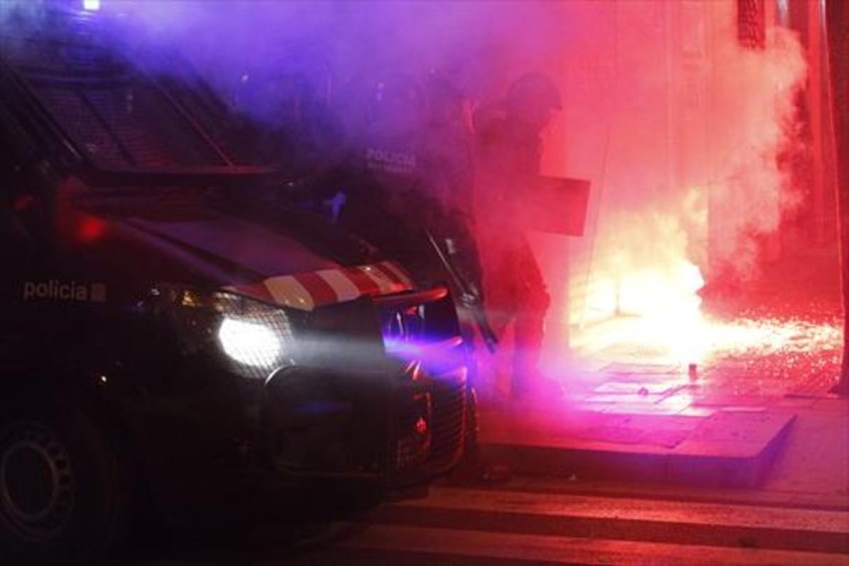 Varios mossos intentan sofocar uno de los incendios provocados en Gràcia.